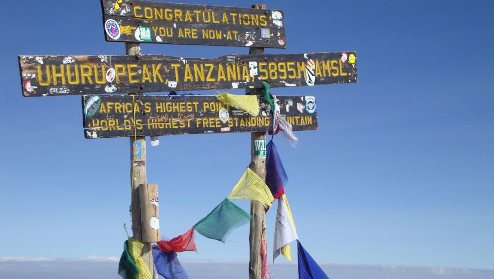 Climbers trekking Mount Kilimanjaro while learning official park fees, permits, camping, and rescue costs for 2026.
