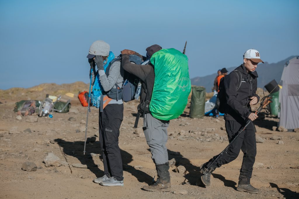 Kilimanjaro porter carrying trekking gear along a mountain trail during a guided climb.