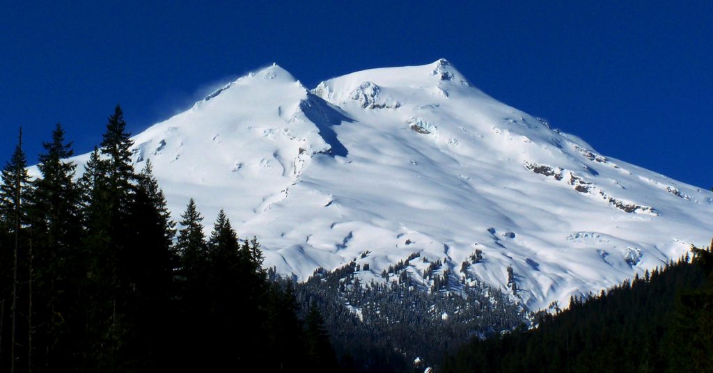 Mount Baker viewed from Boulder Creek showcasing its snow-covered summit, rugged slopes, and surrounding evergreen forest landscapes.