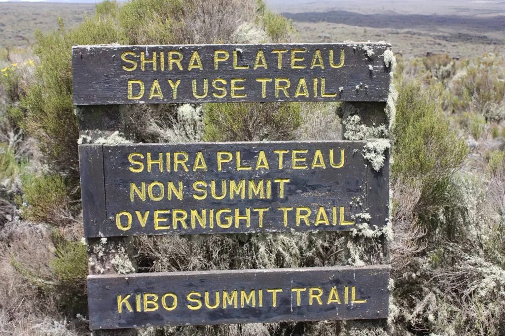 Shira Plateau signboard on Mount Kilimanjaro showing the direction and route information for trekkers.