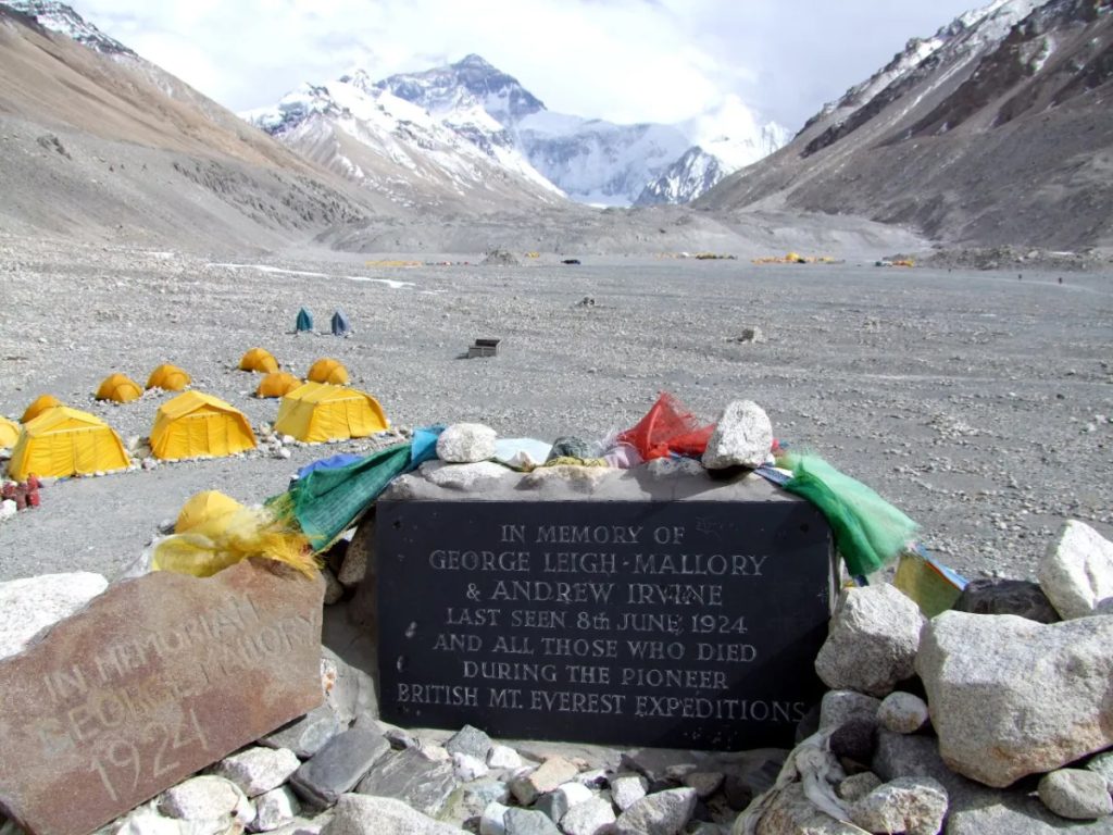 Memorial cairn honoring George Mallory on Mount Everest, surrounded by rocks and the Himalayan mountain landscape.