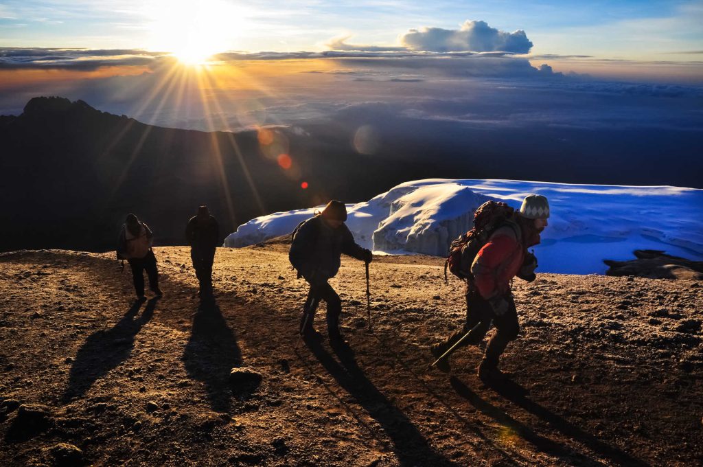 Group of climbers arriving at the Mount Kilimanjaro summit, celebrating their achievement near Uhuru Peak.