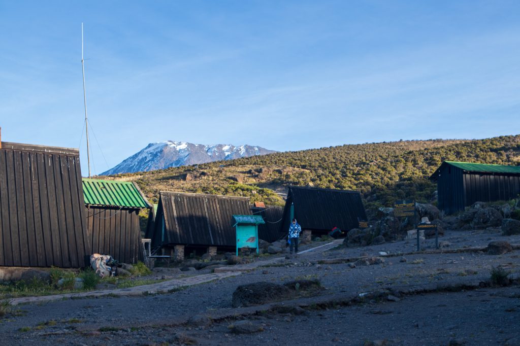 Climbers resting inside Marangu Route huts with bunk beds and dining area during Kilimanjaro ascent.