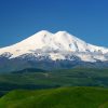 Mount Elbrus snow-covered twin peaks rising above Caucasus Mountains with dramatic alpine landscape in Russia.