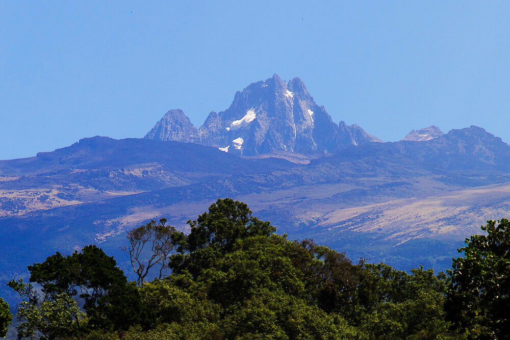 Mount Kenya rises above the surrounding landscape with rugged peaks, glaciers, and alpine vegetation.