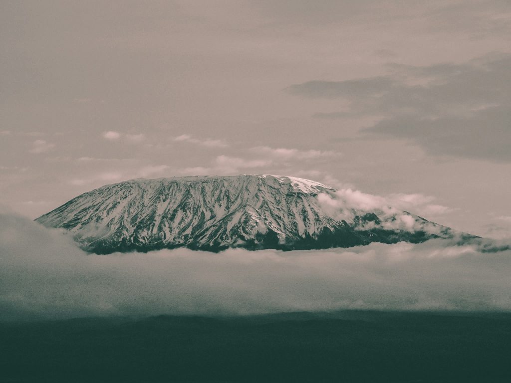 Snow-capped Mount Kilimanjaro rises above the clouds, showcasing Africa's highest peak in northern Tanzania.