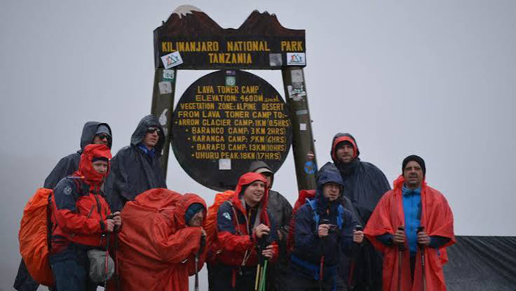 Climbers trekking on Mount Kilimanjaro during the rainy season on a wet and misty mountain trail
