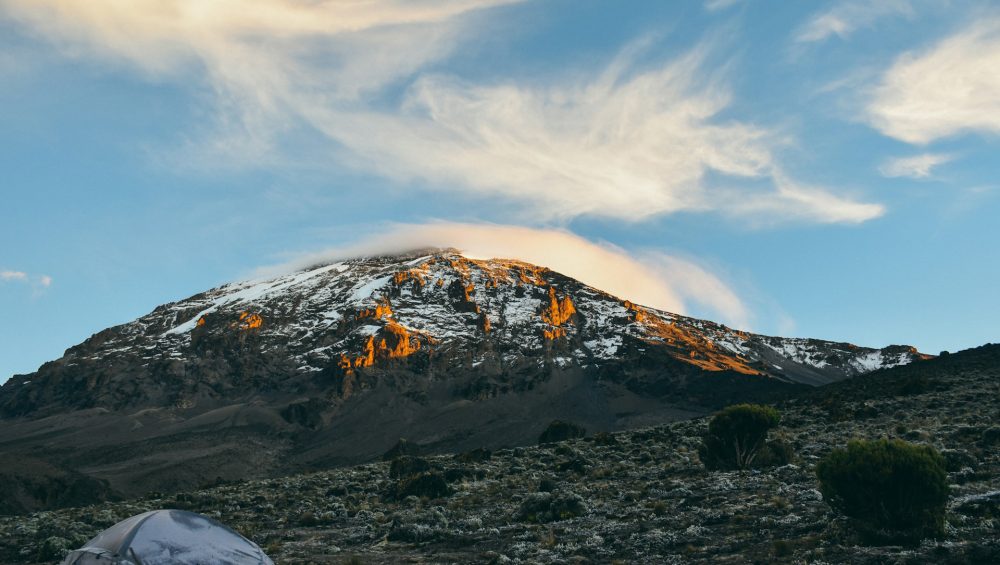 Climbers trekking Mount Kilimanjaro under clear dry season skies showing best time to climb Kilimanjaro.