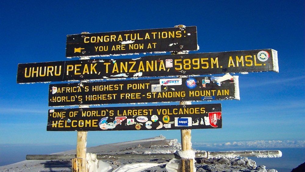 Uhuru Peak summit sign on Mount Kilimanjaro showing Africa’s highest point above the clouds.