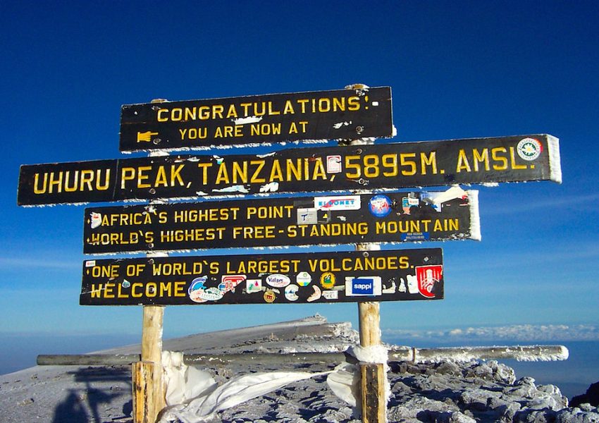 Uhuru Peak summit sign on Mount Kilimanjaro showing Africa’s highest point above the clouds.