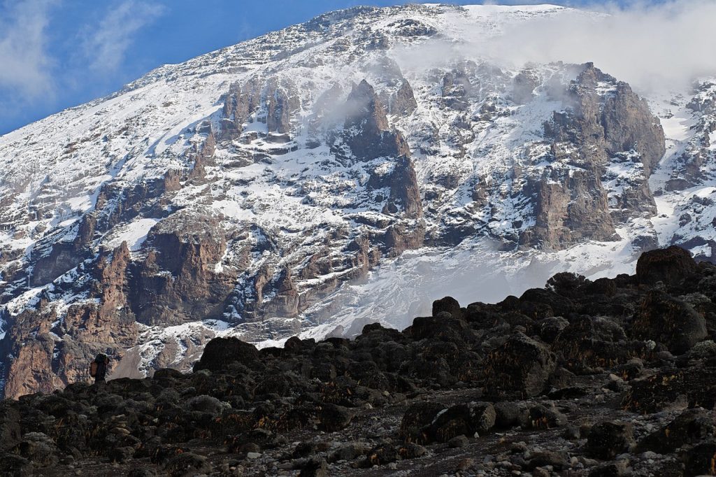 Climber ascending steep rocky trail above Barafu Camp during the challenging final push toward summit.