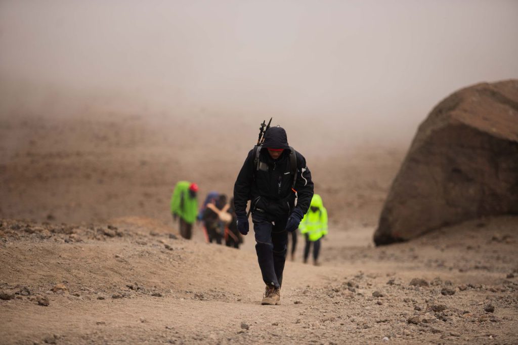 Climbers trekking Mount Kilimanjaro trail with guides during a private mountain expedition adventure.